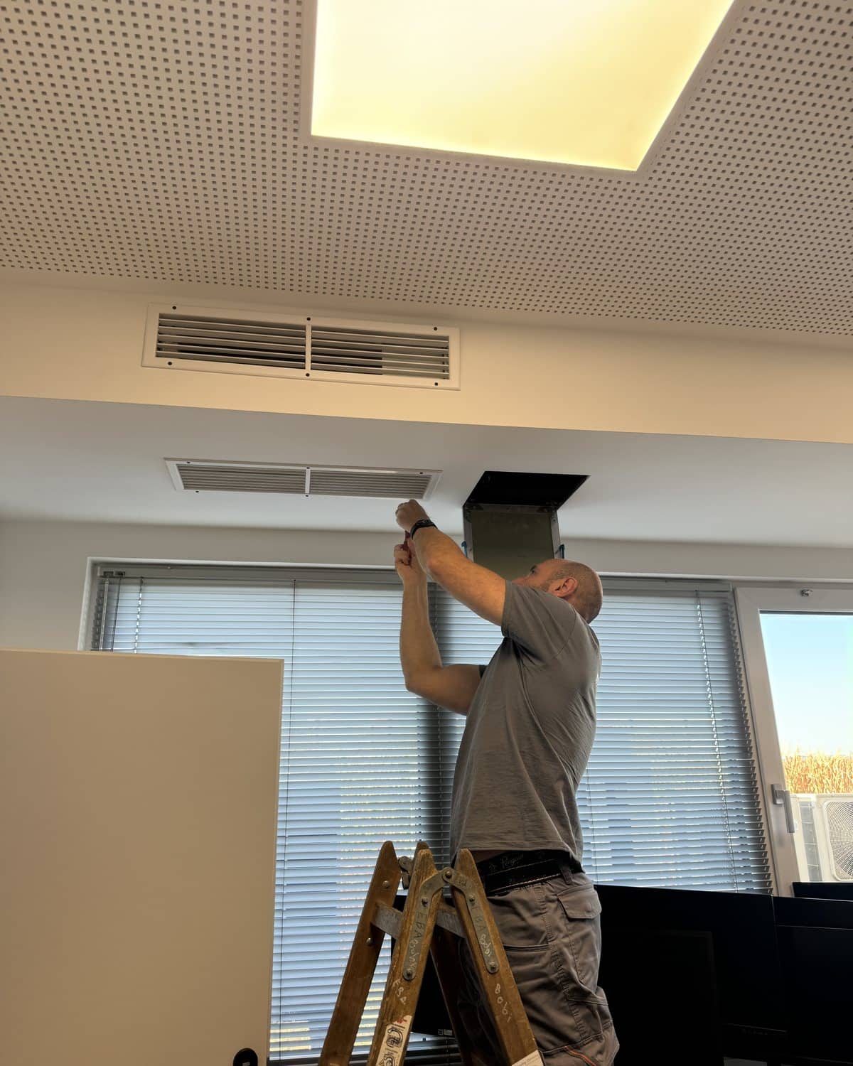 Monteur von Mr Cooling bei Arbeiten an einer Lüftungsanlage in einem Bürogebäude